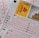 A close-up image of lottery tickets featuring crossed-out numbers, brand logos, and various numbers in a grid format. The tickets have sections for different games, and numbers are marked with black crosses.