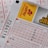 A close-up image of lottery tickets featuring crossed-out numbers, brand logos, and various numbers in a grid format. The tickets have sections for different games, and numbers are marked with black crosses.