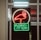 A neon sign depicting a flamingo above the words 'Florida Lottery' is prominently displayed. The sign is illuminated in bright red and green colors, and it is framed by glass panels. An 'EXIT' sign is visible in the background.
