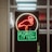 A neon sign depicting a flamingo above the words 'Florida Lottery' is prominently displayed. The sign is illuminated in bright red and green colors, and it is framed by glass panels. An 'EXIT' sign is visible in the background.