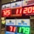 A signboard inside a convenience store displays the current jackpot amounts for various lottery games. There are bright, illuminated numbers in red and green showing the prize amounts: Powerball is at 725 million, Super Lotto Plus at 11 million, Mega Millions at 205 million, Fantasy 5 at 71 thousand, and Daily Derby at 179. In the background, shelves with various drinks and products are visible, along with promotional posters.